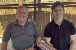 This photo from June 26, 2020 shows Buck Newsome, left, a Baby Boomer, and his son, Chris Newsome, of the Millennial generation, as they pose for a photo while having lunch together in Newtown, Ohio. American's two largest generations can agree on something: the coronavirus pandemic has hit them both hard. For Baby Boomers, named for the post-World War II surge of births, that means those who retired or are nearing retirement age are seeing their retirement accounts in a free fall. Millennials, usually defined as those born between 1981 and 1996, who became adults in this century, are getting socked as they were trying to begin careers or moving into peak earning years after many walked off college campuses into the Great Recession. (AP Photo/Dan Sewell)