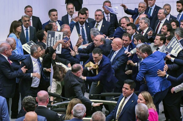 Pro-Kurdish Peoples' Equality and Democracy Party, or DEM, and Justice and Development Party, or AKP, lawmakers scuffle at the parliament in Ankara, Tuesday, June 4, 2024. More than a dozen legislators from Turkey's pro-Kurdish party staged a demonstration in parliament on Tuesday to denounce the arrest and expulsion from office of a newly-elected mayor, Turkish media reported. Boards read in Turkish: "Municipalities are ours. We will not allow extortion". (Mustafa Istemi/Dia Photo via AP)