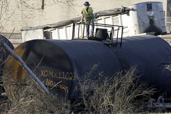  FILE - A cleanup worker stands on a derailed tank car of a Norfolk Southern freight train in East Palestine, Ohio, continues, Feb. 15, 2023. The National Transportation Safety Board’s daylong hearing on what caused the East Palestine derailment and how to prevent similar disasters gave the community,  railroads and policymakers plenty to think about. (AP Photo/Gene J. Puskar, File)