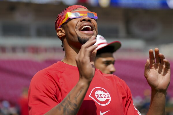 Cincinnati Reds' Will Benson reacts to the sun during a solar eclipse before a baseball game against the Milwaukee Brewers in Cincinnati, Monday, April 8, 2024. (AP Photo/Aaron Doster)