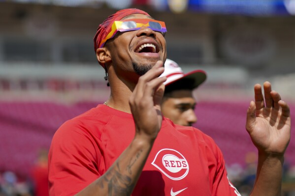 Cincinnati Reds' Will Benson reacts to the sun during a solar eclipse before a baseball game against the Milwaukee Brewers in Cincinnati, Monday, April 8, 2024. (AP Photo/Aaron Doster)