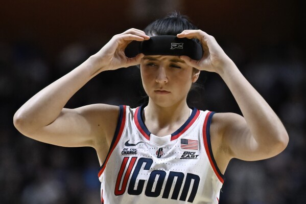 UConn guard Caroline Ducharme adjusts a protective headband during the second half of an NCAA college basketball game against St. John's in the quarterfinals of the Big East Conference tournament, Saturday, March 8, 2025, in Uncasville, Conn. (AP Photo/Jessica Hill)