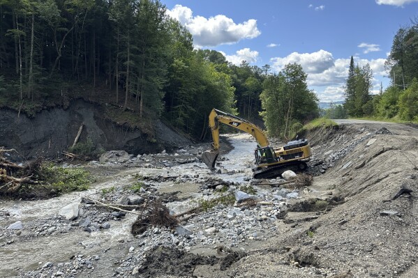 An excavator works to stabilize a flooded brook in Lyndon, Vt., on Wednesday, Aug. 7, 2024. (AP Photo/Lisa Rathke)