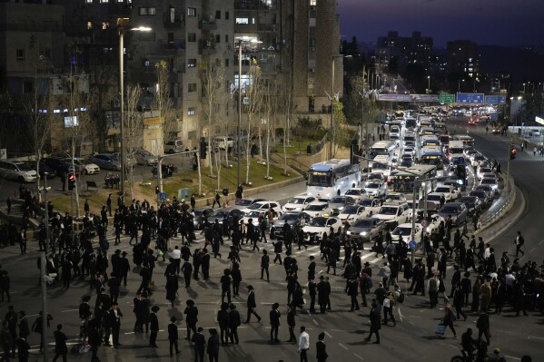 FILE - Ultra-Orthodox Jewish men and boys block a road during a protest against the country's military draft in Jerusalem, on Feb. 26, 2024.  (AP Photo/Leo Correa, File)