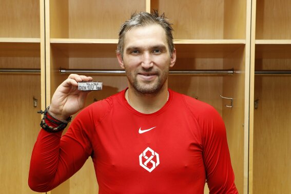 Washington Capitals' Alex Ovechkin poses with the puck commemorating his 700th career NHL goal that he scored against the New Jersey Devils in the third period at Prudential Center on Saturday, Feb. 22, 2020, in Newark, New Jersey. (Patrick McDermott/NHLI Pool Photo via AP)