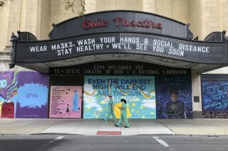 Workers in scrubs and masks walk past the Ohio Theatre in Columbus, Ohio, Wednesday, Aug. 26, 2020, amid the coronavirus pandemic. (AP Photo/Julie Carr Smyth)