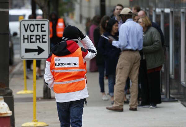 
              An election official, left, maintains the crowd line and parking spaces as people line up to vote at the Minneapolis Early Vote Center on the last day of early voting Monday, Nov. 5, 2018, in Minneapolis. The Associated Press will debut a new survey of the nation's electorate that aims to more accurately capture the story of how Americans vote and why in Tuesday's midterm elections. (AP Photo/Jim Mone)
            