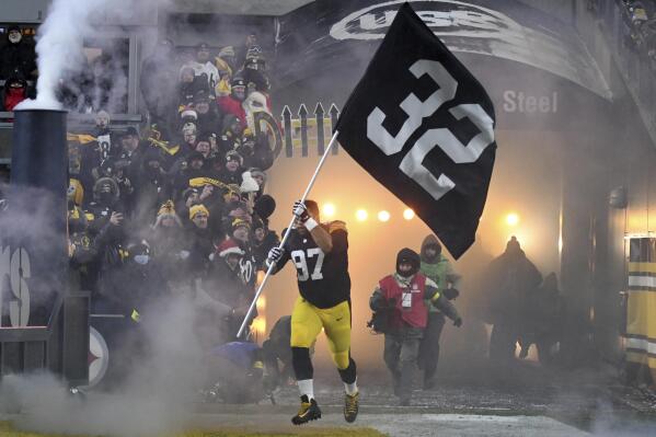 Pittsburgh Steelers defensive tackle Cameron Heyward (97) carries a banner with the uniform number of Pittsburgh Steelers' Franco Harris as he is introduced before an NFL football game against the Las Vegas Raiders in Pittsburgh, Saturday, Dec. 24, 2022. (AP Photo/Fred Vuich)