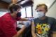 Nurse Carole Weaver, left, gives a COVID-19 vaccination shot to thirteen-year-old Jesse James, of Pleasantville, Iowa, Monday, Aug. 16, 2021, in Des Moines, Iowa. At the Iowa State Fair in Des Moines, where a million people are expected for the 11-day event, public health officials hope a vaccination station set up by pharmacists working for the Hy Vee food store chain will entice some of the vaccine-hesitant to get their shots. Visitors are packing in to state fairs in multiple Midwest states as COVID activity is increasing, raising concerns about the potential for rapidly accelerating spread of the delta variant of the COVID-19 virus. (AP Photo/Charlie Neibergall)