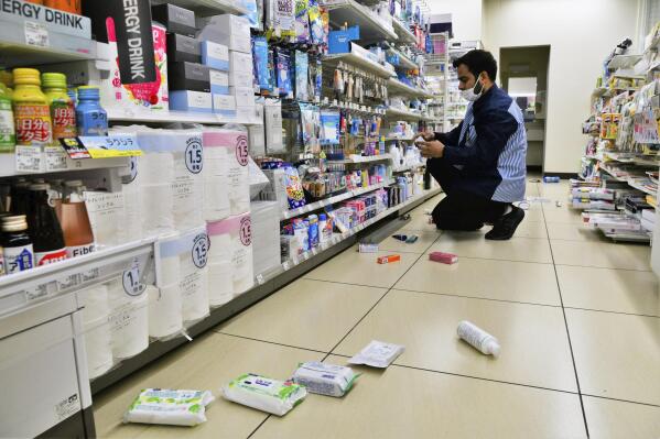 An employee clears products fallen from shelves at a convenience store in Iwaki, Fukushima prefecture, northern Japan Wednesday, March 16, 2022, following an earthquake. A powerful earthquake shook off the coast of Fukushima in northern Japan on Wednesday, triggering a tsunami advisory. (Kyodo News via AP)
