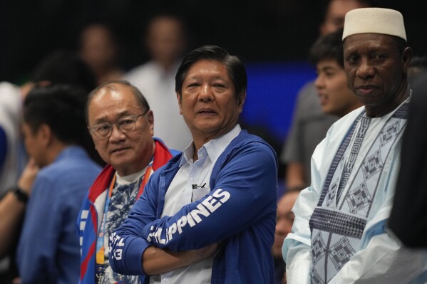 Philippine President Ferdinand Marcos Jr., center, watches the game beside FIBA president Hamane Niang, right, during a match of the Philippines against Dominican Republic at the Basketball World Cup at the Philippine Arena in Bulacan province, Philippines Friday, Aug. 25, 2023. (AP Photo/Aaron Favila)