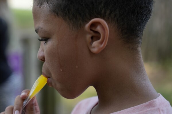 Zariah Fields eats a popsicle, Thursday, June 20, 2024, at YMCA Camp Kern in Oregonia, Ohio. As the first heat wave of the season ripples across the U.S., summer camps are working to keep their children cool while still letting the kids enjoy being outside with nature. (ĢӰԺ Photo/Joshua A. Bickel)