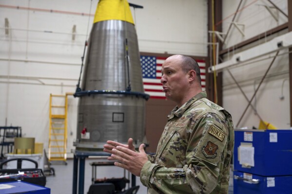 In this image provided by the U.S. Air Force, Chief Master Sgt. Andrew Zahm speaks in front of the top of a Minuteman III intercontinental ballistic missle shroud at F.E. Warren Air Force Base, Wyo., Aug. 16, 2023. Zahm has worked on the military's nuclear missile mission for 21 years. The increased workload of maintaining old missiles with fewer people has made it harder to convince younger troops to stay, especially because with their critical skillset they could make much more money in the private sector. (Senior Airman Sarah Post/U.S. Air Force via AP)