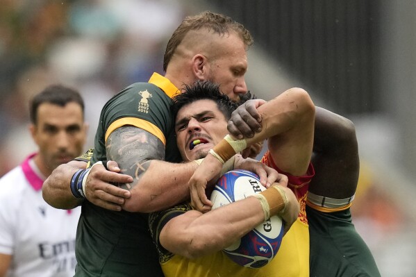 Romania's Marius Simionescu, center, is tackled by South Africa's RG Snyman, left, during the Rugby World Cup Pool B match between South Africa and Romania at the Stade de Bordeaux in Bordeaux, France, Sunday, Sept. 17, 2023. (AP Photo/Themba Hadebe)