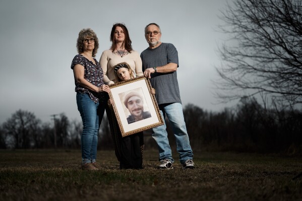 Eight-year-old Estella Baraniak, accompanied by her mother, Ashley Snyder, and grandparents Jackie and Brian Baraniak pose for a photograph with an image of her deceased father, Matthew Baraniak, in Halifax, Pa., Wednesday, March 6, 2024. Across the country, it's not uncommon for the relatives of prisoners who died on the job to struggle with determining who's liable. When workers' compensation is offered, the amount awarded is typically determined by the size of the worker's paycheck and usually closes the door on future wrongful death suits. (AP Photo/Matt Rourke)