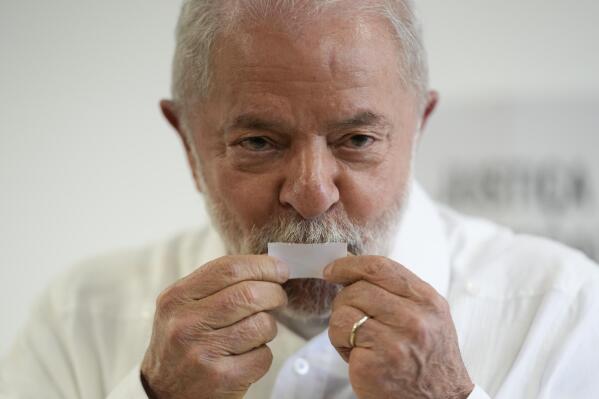 Former Brazilian President Luiz Inacio Lula da Silva kisses his ticket after voting in a run-off presidential election in Sao Paulo, Brazil, Sunday, Oct. 30, 2022. Twenty years after first winning the Brazilian presidency, da Silva, universally known as Lula, defeated incumbent Jair Bolsonaro in an extremely tight election. (AP Photo/Andre Penner)