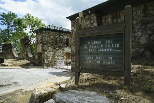 A sign, frozen in time after flooding last fall, stands at the entrance to the closed state park in Chimney Rock Village, N.C., on Wednesday, May 14, 2025. (AP Photo/Allen G. Breed)