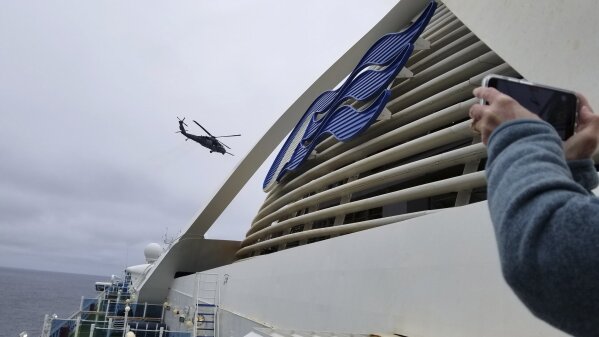 CORRECTS FROM COAST GUARD TO NATIONAL GUARD HELICOPTER- In this photo provided by Michele Smith, a National Guard  helicopter delivering virus testing kits hovers above the Grand Princess cruise ship Thursday, March 5, 2020, off the California coast. Scrambling to keep the coronavirus at bay, officials ordered a cruise ship with about 3,500 people aboard to hold off the California coast Thursday until passengers and crew could be tested, after a traveler from its previous voyage died and at least one other became infected. Princess Cruises says fewer than 100 of those aboard have been identified for testing. (Michele Smith via AP)
