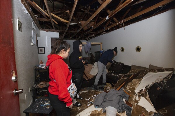 File - Jorge Amezquita, from right, cousin Adalene Castillo and girlfriend Cassandra Duarte look for a TV remote under debris after a tornado ripped the roof off the apartment on Jan. 24, 2023, at Beamer Place Apartments in Houston. When natural or manmade disasters happen, renters insurance can mean the difference between catastrophe and stability. (Yi-Chin Lee/Houston Chronicle via Ǻ, File)