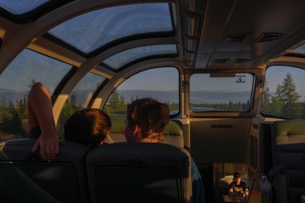 Passengers relax inside the skyline car as the sun sets Thursday, Aug. 8, 2024, between Churchill and Gilliam, Manitoba. (AP Photo/Joshua A. Bickel)