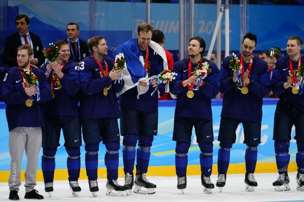 Finland's Marko Anttila, center, is draped with a flag as players are presented their gold medals after defeating Russian Olympic Committee in the men's gold medal hockey game at the 2022 Winter Olympics, Sunday, Feb. 20, 2022, in Beijing. (AP Photo/Matt Slocum)