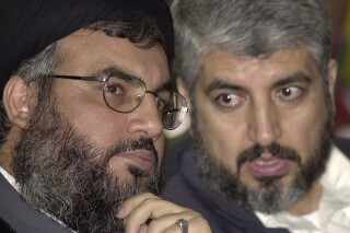 Tư liệu - Sheik Hassan Nasrallah, lãnh đạo Hezbollah, trái, trò chuyện với Khaled Mashaal, ở phía nam Beirut, Lebanon, ngày 27 tháng 3 năm 2004. Quốc gia giàu khí đốt Qatar đã trở thành bên trung gian quan trọng cho số phận của khoảng 200 con tin bị bắt giữ bởi Hamas sau cuộc tấn công chưa từng có vào Israel, một lần nữa khiến Bán đảo Ả Rập nhỏ bé trở thành tâm điểm chú ý.  (Ảnh AP/Hassan Ammar, Tệp)