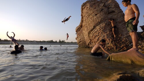 Iraqi men and their sons swim in the Tigris river to beat the heat in Baghdad, Iraq, Thursday, July 13, 2023. (AP Photo/Hadi Mizban)