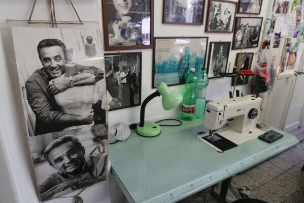 A picture of Umberto Tirelli, left, is displayed near a sewing machine at the Tirelli Atelier in Rome, Tuesday, March 5, 2024. For nearly six decades, the Tirelli atelier in Rome has woven itself into the fabric of Italian and international film history, earning the nickname the "Oscar tailor's shop" for its contribution to cinematic costume design. Established in November 1964, the shop on a quiet Roman street has been behind 17 Academy Awards for Best Costume Design. (AP Photo/Gregorio Borgia)
