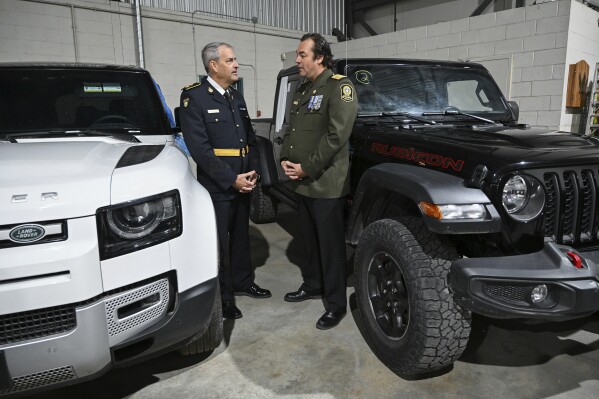 Deputy Commissioner Marty Kearns, Investigations and Organized Crime at the Ontario Provincial Police, left, talks with Deputy Chief Benoit Dube of the Surete du Quebec, beside two recovered stolen vehicles during a news conference in Montreal, Wednesday, April 3, 2024. Ontario Provincial Police and the Canada Border Services Agency say they've seized hundreds of stolen cars that were destined for export at the Port of Montreal. (Graham Hughes/The Canadian Press via AP)