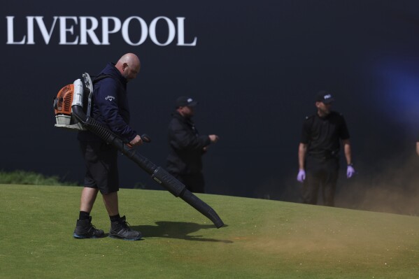 Green-keepers clear away debris after protesters threw material onto the 17th green during the second day of the British Open Golf Championships at the Royal Liverpool Golf Club in Hoylake, England, Friday, July 21, 2023. (AP Photo/Peter Morrison)