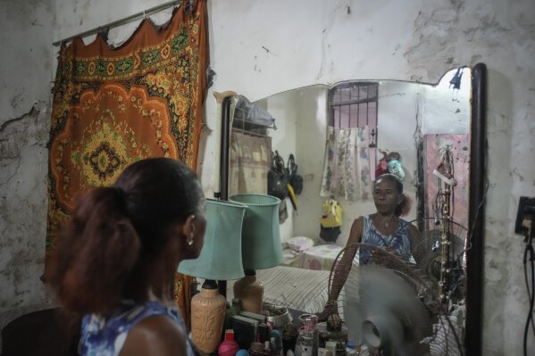 Maricelys Colás poses for a portrait in the mirror of her bedroom inside the dilapidated mansion where she lives with five other families on Villegas Street in Havana, Cuba, Thursday, Oct. 5, 2023. (AP Photo/Ramon Espinosa)