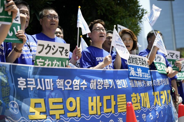 South Korean lawmakers hold placards and a banner against Japanese plans to release treated radioactive water from the damaged Fukushima nuclear power plant, during a rally in front of the Prime Minister's office Monday, July 10, 2023, in Tokyo. The small green placards in Japanese read, "(We) don't forget Fukushima!" The banner in Korean reads, "No dumping of Fukushima nuclear contaminated water at sea!," upper line, and "Let’s protect everyone’s sea together." (AP Photo/Eugene Hoshiko)