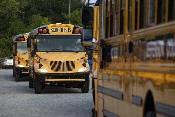 Jefferson County Public Schools school buses packed with students makes their way through the Detrick Bus Compound on the first day of school Wednesday, Aug. 9, 2023, in Louisville, Ky. Kentucky’s largest school system has cancelled the second and third day of school after a disastrous overhaul of the transportation system that left some children on buses until almost 10 p.m. on opening day. Jefferson County Public Schools Superintendent Marty Pollio calls it a “transportation disaster” in a video posted on social media. (Jeff Faughender/Courier Journal via AP)