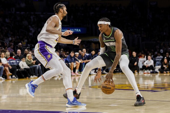 Minnesota Timberwolves forward Jaden McDaniels (3) dribbles past Los Angeles Lakers guard Spencer Dinwiddie (26) during the first half of an NBA basketball game, Sunday, April 7, 2024, in Los Angeles. (AP Photo/Etienne Laurent)