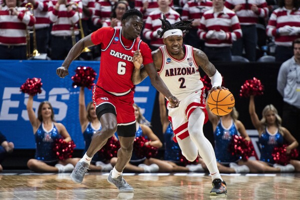 Arizona guard Caleb Love (2) brings the ball up court while guarded by Dayton guard Enoch Cheeks (6) during the first half of a second-round college basketball game in the NCAA Tournament in Salt Lake City, Saturday, March 23, 2024. (AP Photo/Isaac Hale)