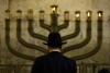 FILE - An Ultra-Orthodox Jewish man stands in front of a menorah on the third eve of Hanukkah, at the Western Wall, Judaism's holiest site in Jerusalem's old city, Sunday, Dec. 13, 2009. On eight consecutive nightfalls, Jews gather with family and friends to light one additional candle in the menorah candelabra. They do so to commemorate the rededication of the Temple in Jerusalem in the 2nd century BC, after a small group of Jewish fighters liberated it from occupying foreign forces. (AP Photo/Sebastian Scheiner, File)