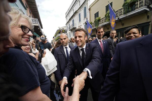 French President Emmanuel Macron greets the crowd as he walks down Royal Street in the French Quarter of New Orleans, Friday, Dec. 2, 2022. (AP Photo/Gerald Herbert)