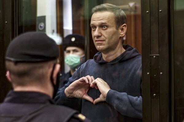 FILE - In this handout photo taken from video provided by the Moscow City Court on Feb. 2, 2021, Russian opposition leader Alexei Navalny shows a heart symbol while standing in a defendants’ cage during a hearing in the Moscow City Court in Moscow, Russia. Navalny, who died in an Arctic penal colony on Feb. 16, spent months in punishment cells for infractions like not buttoning his uniform properly or not putting his hands behind his back when required. (Moscow City Court via AP, File)