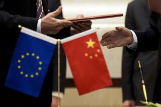 FILE - A member of European Commission, left, prepares to exchange documents with Chinese delegation at a signing ceremony after the 5th China-EU High Level Economic and Trade dialogue at Diaoyutai State Guest House in Beijing, on Sept. 28, 2015. China has accused the European Union of protectionism and “reckless distortion” of the definition of subsidies in response to a new EU investigation into Chinese wind turbine makers. (AP Photo/Andy Wong, File)
