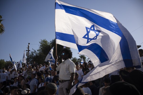 2024年6月5日，星期三，在耶路撒冷老城大马士革门前，以色列人在纪念耶路撒冷日的游行中挥舞国旗。耶路撒冷日是以色列庆祝在1967年中东战争中占领东耶路撒冷的节日。数千名以极端民族主义为主的以色列人参加了一年一度的游行，途经耶路撒冷一个敏感的巴勒斯坦地区，一些人高呼“阿拉伯人去死吧”，加剧了战时紧张局势