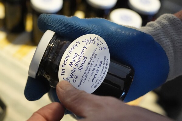 Hugh Lassen adds a label to a jar of wild blueberry spread, Monday, Feb. 10, 2025, in Cherryfield, Maine. (AP Photo/Robert F. Bukaty)