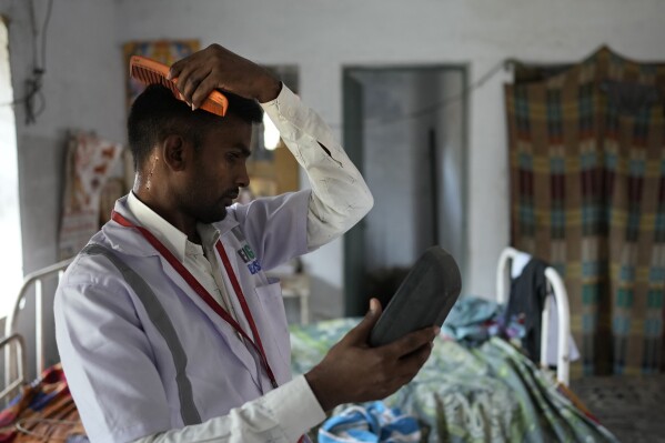 Jitendra Kumar, a paramedic who travels in an ambulance, sweats while he gets ready for duty in a room he shares with several others at the district government hospital quarters, in Banpur in the Indian state of Uttar Pradesh, Sunday, June 18, 2023. Ambulance drivers and other healthcare workers in rural India are the first line of care for those affected by extreme heat. (AP Photo/Rajesh Kumar Singh)
