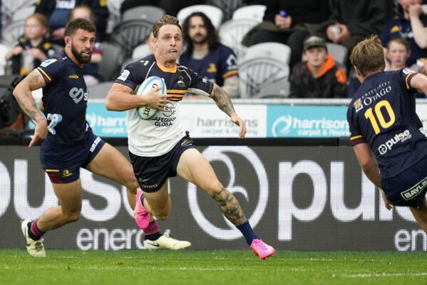Brumbies Corey Toole, center, runs past defenders to score a try during the Super Rugby Pacific match between the Highlanders and the ACT Brumbies at Forsyth Barr Stadium in Dunedin, New Zealand, Saturday, March 16, 2024. (Michael Thomas/AAP Image via AP)