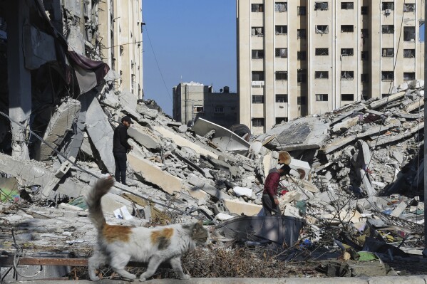 2024年1月19日金曜日、ガザ地区のヌセイラト難民キャンプでイスラエルの爆撃による荒廃の中を歩くパレスチナ人たち（AP写真/アデル・ハナ）