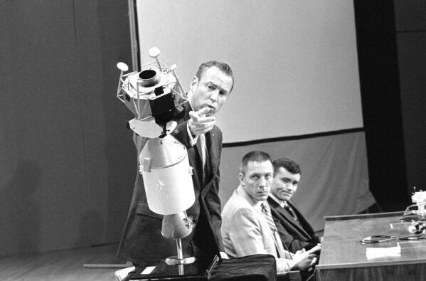 Apollo 13 commander James A. Lovell Jr., uses a scale model to explain how the crew managed to survive the explosion that damaged the service module during the flight to the moon. Tense as they relive the terrifying moments, April 21, 1970 at the televised news conference at Manned Spacecraft Center Houston, Tex., at night are: John L. Swigert Jr., center, command module pilot, and Fred W. Haise Jr., lunar module pilot. (AP Photo)
