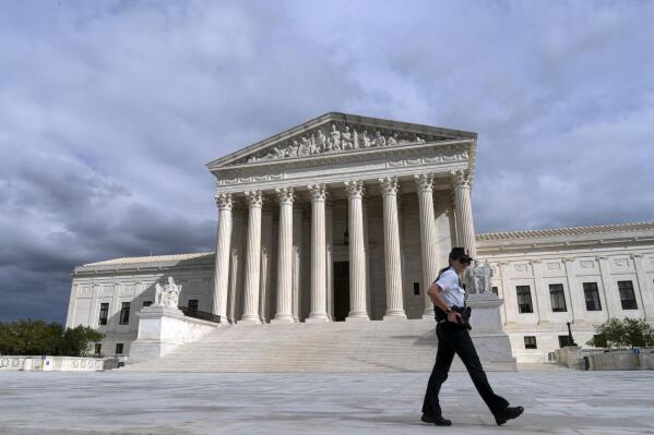 A police officer walks by during a voting rights rally, at the U.S. Supreme Court Thursday, Oct. 28, 2021, in Washington. (AP Photo/Jose Luis Magana)