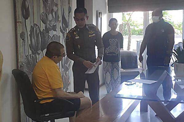 Peter Coker Jr., left, is issued search warrants from police at his villa on the southern resort island of Phuket, Thailand, Jan. 11, 2023. Coker Jr., who used to work in Hong Kong and who is wanted in connection with an alleged stock manipulation scheme that led a small New Jersey delicatessen to be listed as a public company worth $100 million, has agreed to his voluntary extradition to the United States after being arrested last week on the resort island of Phuket, a Thai legal official said Friday, Jan. 20, 2023. (Crime Suppression Division, Royal Thai Police. via AP)