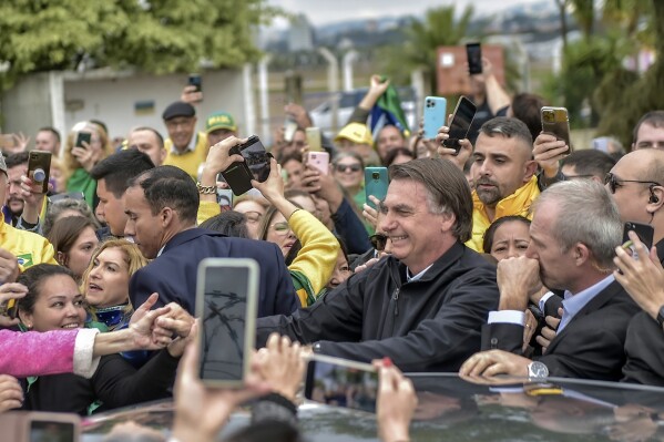 Brazil's former President Jair Bolsonaro is greeted by supporters after landing at the airport in Porto Alegre, Brazil, Thursday, June 22, 2023. Brazil’s top electoral court on Thursday began hearing a case which claims the he abused his power by using government communication channels to promote his campaign and cast unfounded doubts on the country’s electronic voting system, which could render him ineligible for public office for eight years. (AP Photo/Wesley Santos)