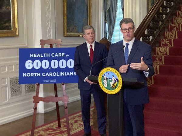 North Carolina Health and Human Services Secretary Kody Kinsley, right, speaks while Gov. Roy Cooper listens at an Executive Mansion news conference in Raleigh, N.C., on Monday, Sept. 25, 2023. Kinsley and Cooper announced that North Carolina would launch Medicaid expansion coverage on Dec. 1. Expansion will be able to start because Cooper said he'll let a state budget bill sent by the General Assembly last week to his desk become law without his signature. (AP Photo/Gary D. Robertson)