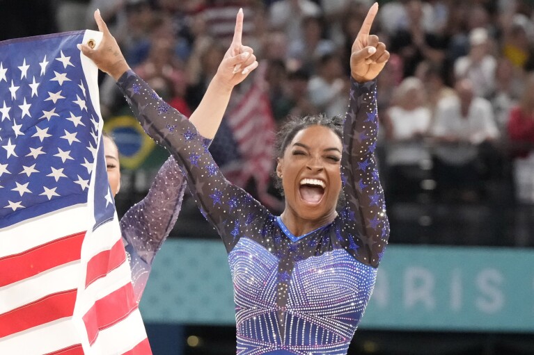 Simone Biles, of the United States, celebrates after winning the gold medal during the women's artistic gymnastics all-around finals in Bercy Arena at the 2024 Summer Olympics, Thursday, Aug. 1, 2024, in Paris, France. (AP Photo/Charlie Riedel)
